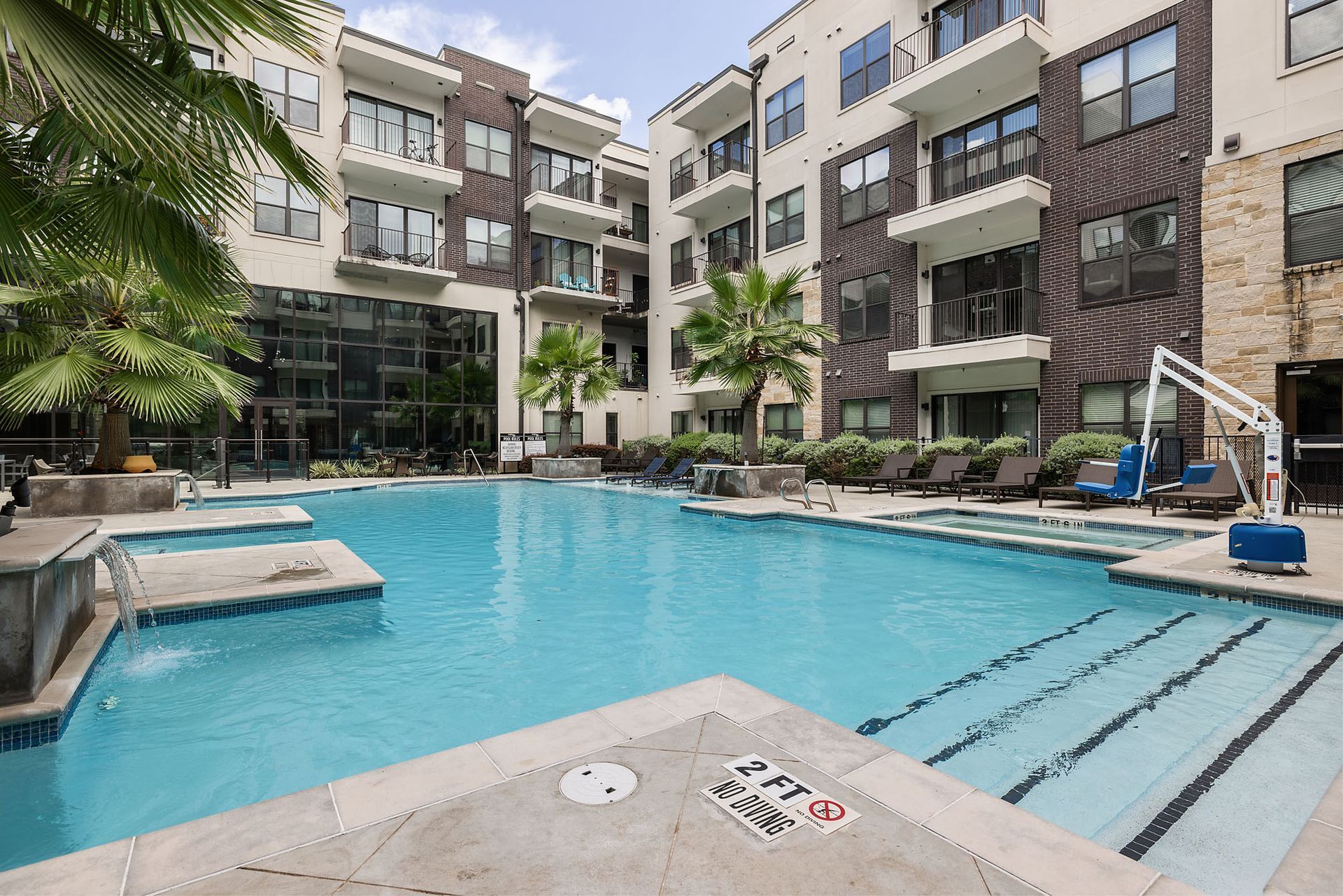 Apartment courtyard pool with turquoise water, lounge chairs, and surrounding balconies.