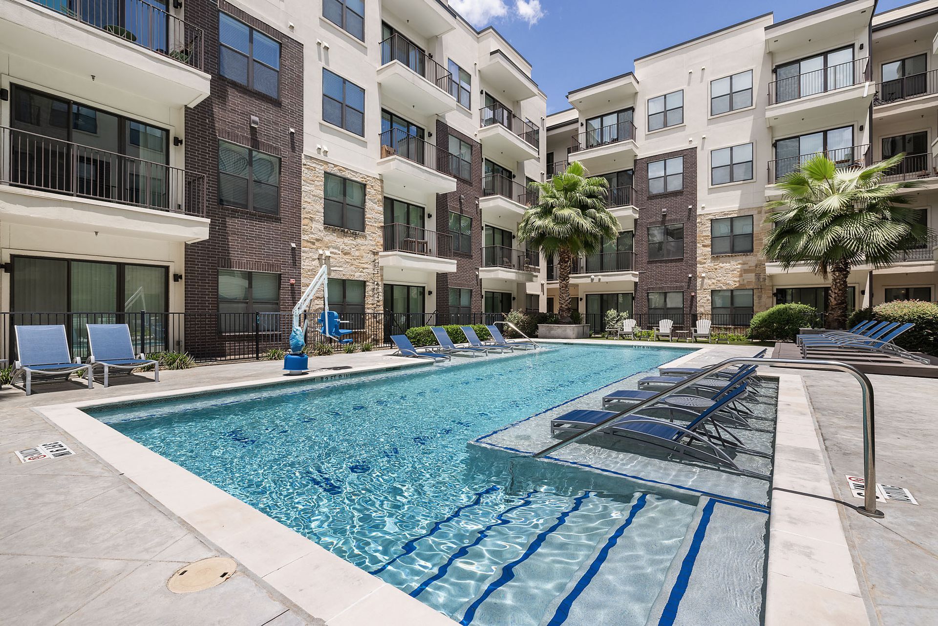 Apartment courtyard pool with lounge chairs and surrounding modern buildings