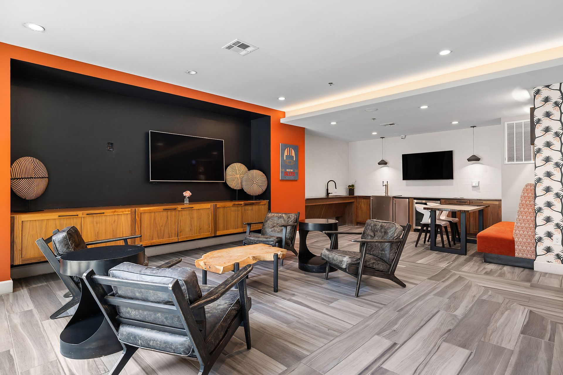 Modern lounge with black accent wall, mounted TV, leather chairs, and dining area in the background