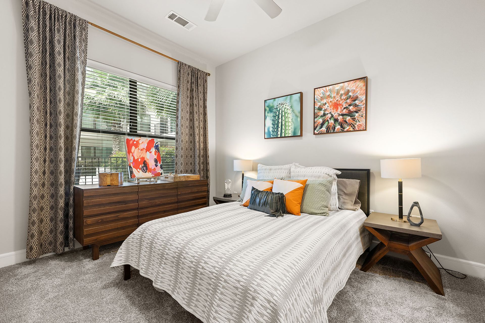 Bright bedroom with a bed, bedside lamp, window seat, and patterned curtains
