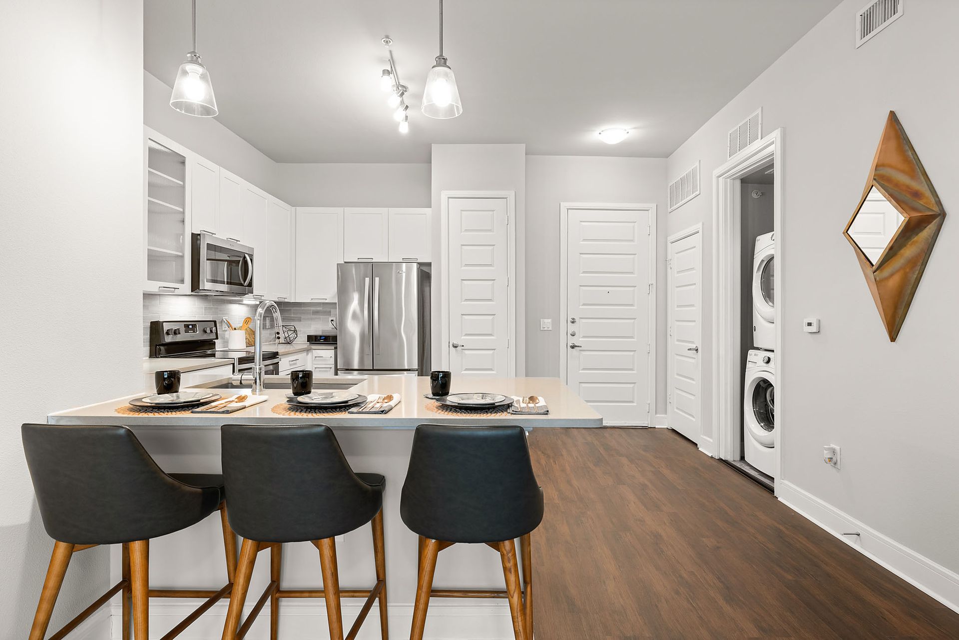 Modern kitchen with island seating, stainless steel appliances, white cabinets, and pendant lights
