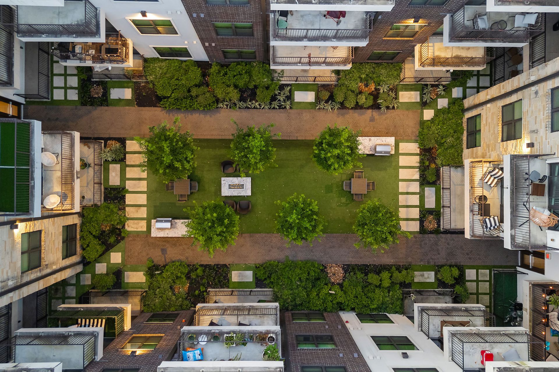 Top-down view of a courtyard garden with paths, benches, trees, and surrounding apartment buildings.