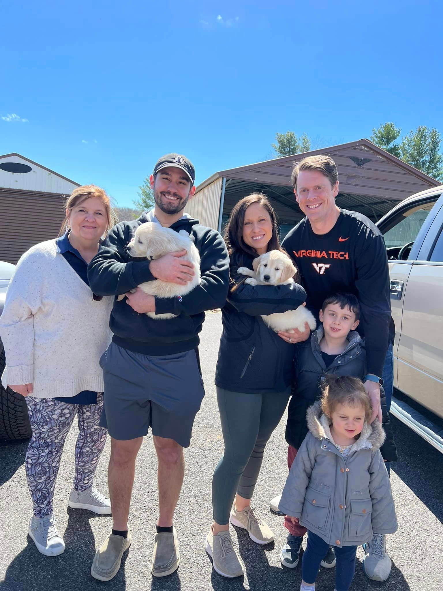A group of people standing next to each other holding a puppy.