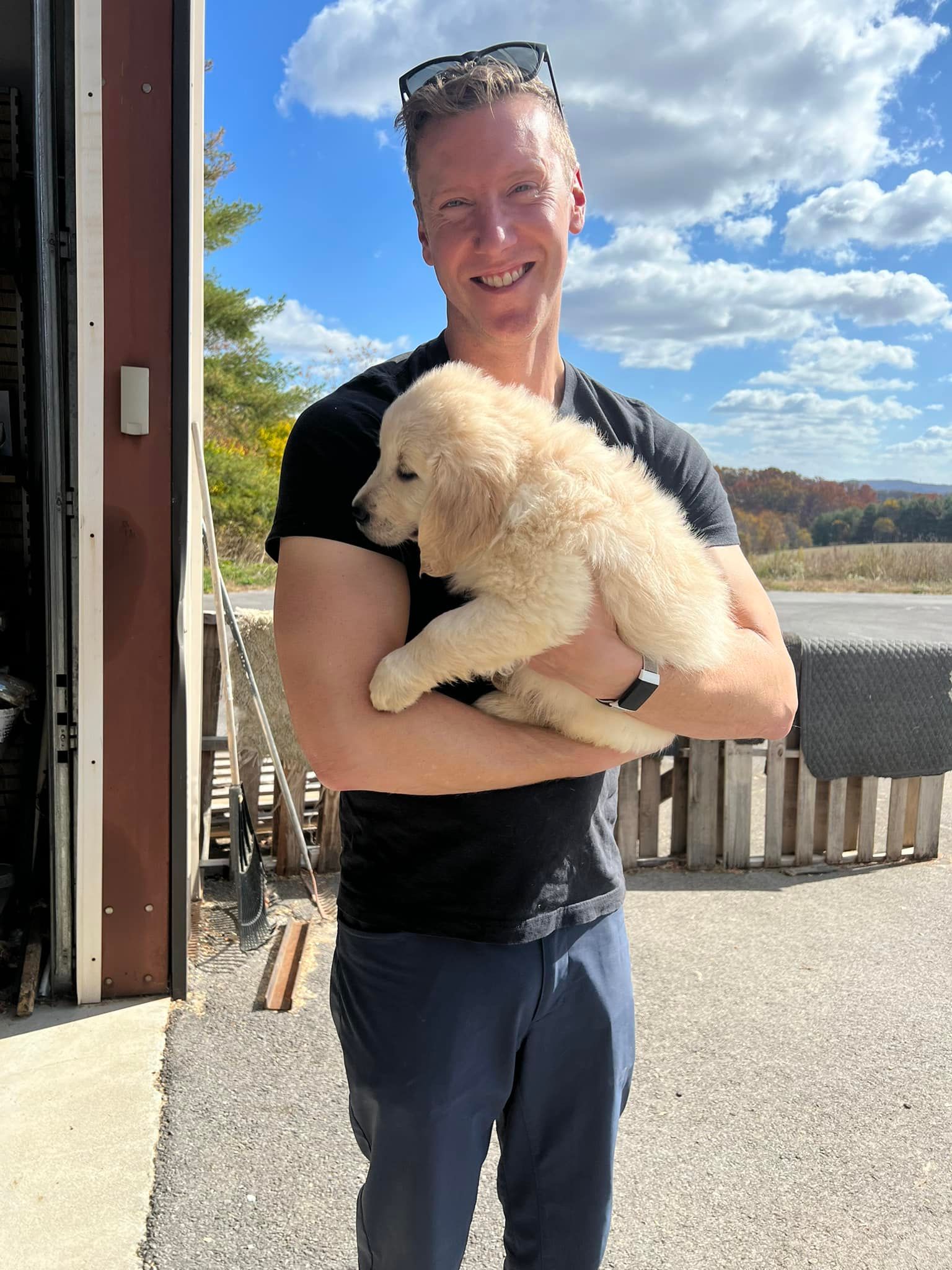 A man is holding a puppy in his arms in front of a garage door.