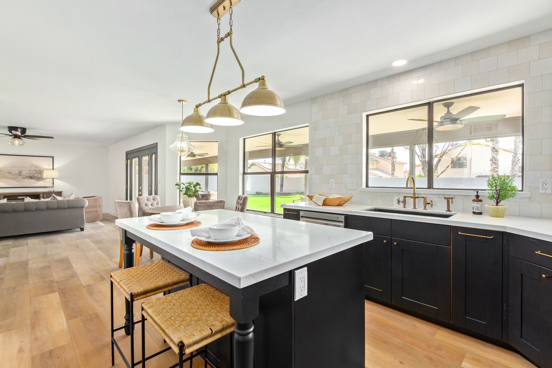 A kitchen with black cabinets , white counter tops , and a large island.