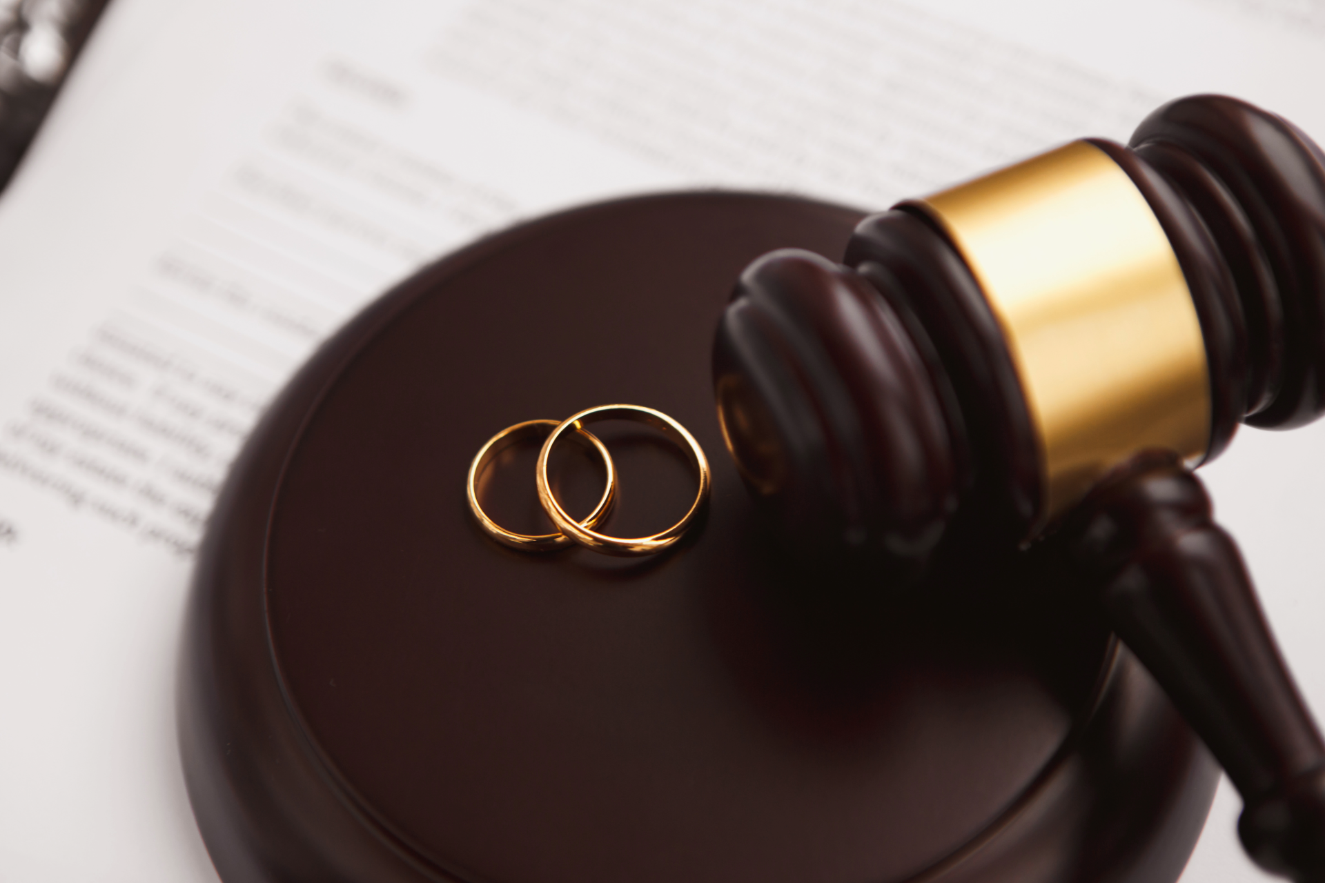 Wedding rings beside a judge’s gavel on a legal document, symbolizing divorce