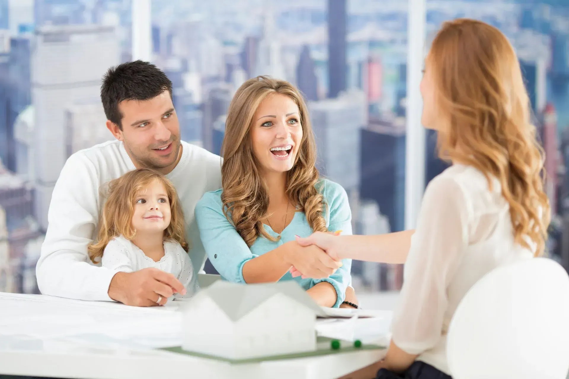 A family is shaking hands with a real estate agent.