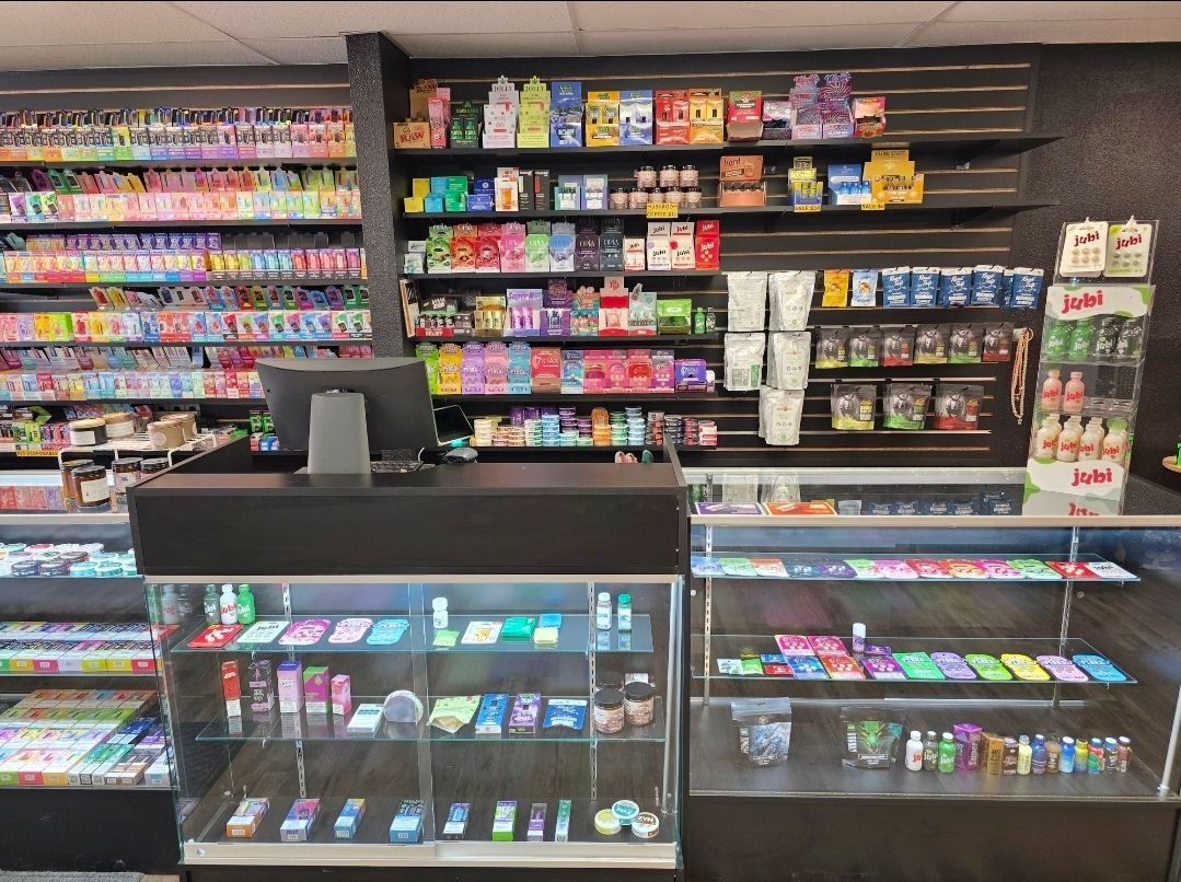 A shop interior featuring a counter and glass display cases filled with various colorful merchandise and shelves of items.