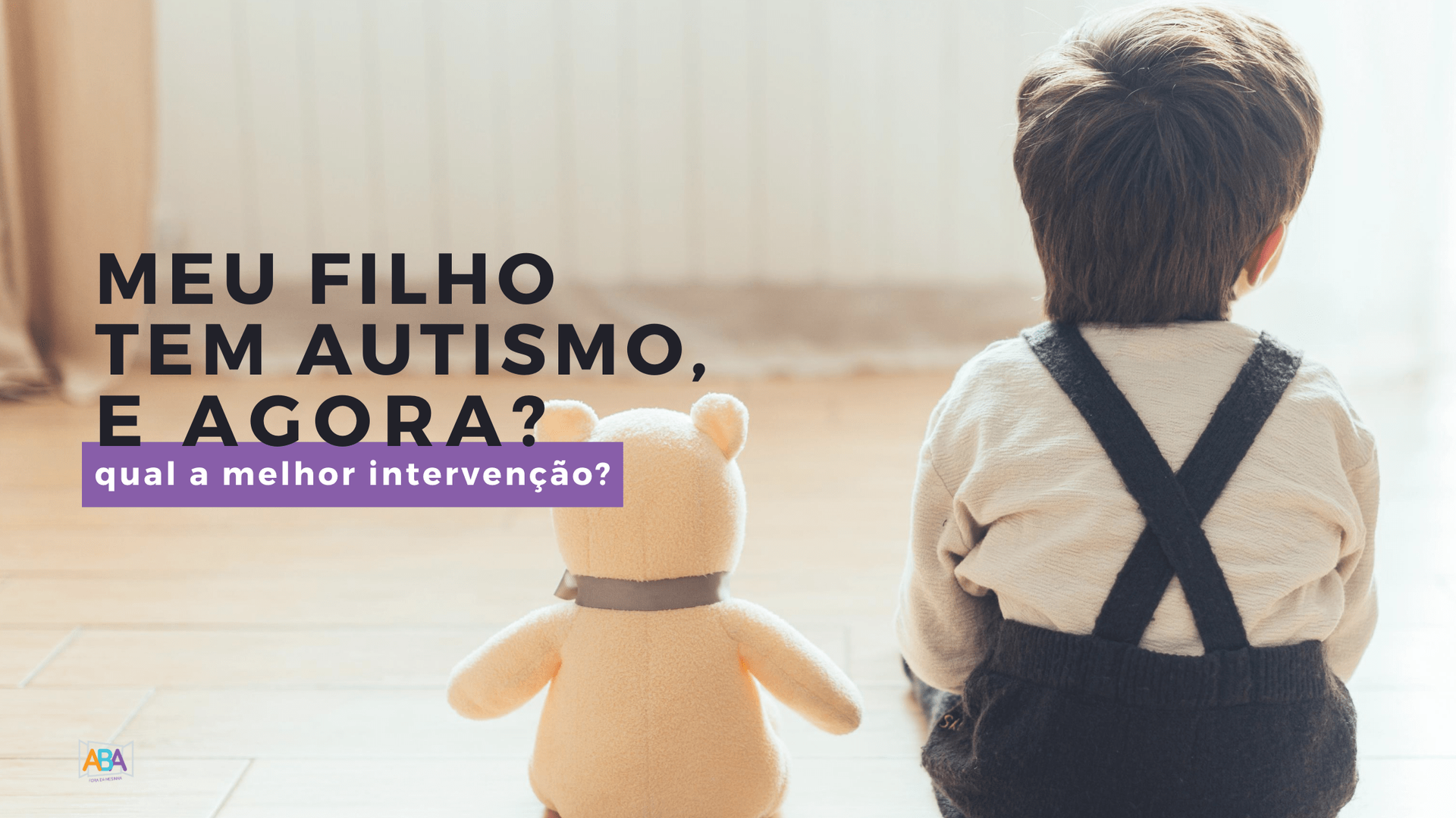 Um menino está sentado ao lado de um ursinho de pelúcia no chão.