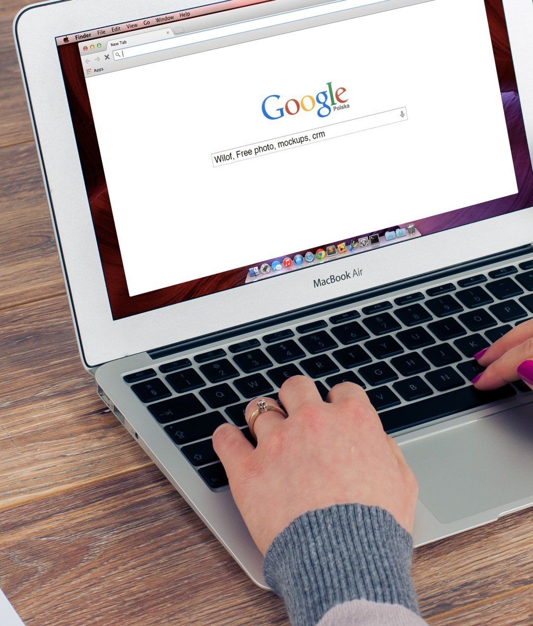 A person is typing on a laptop with google on the screen