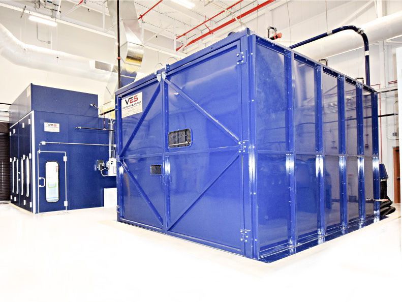 Large blue VES blast enclosure next to blue VES paint booth installed inside a facility.