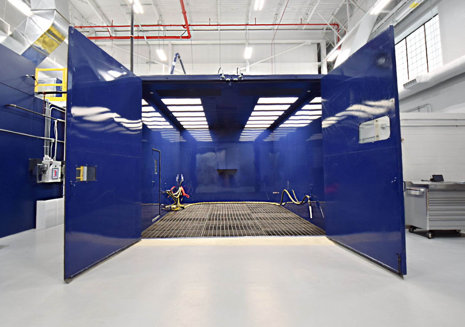 Interior of a blue VES abrasive blast room with doors open showing interior inside a facility