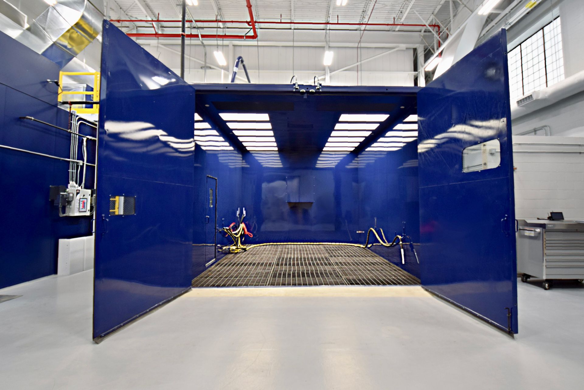 Blue VES blast enclosure with doors open showing the interior installed inside a facility.