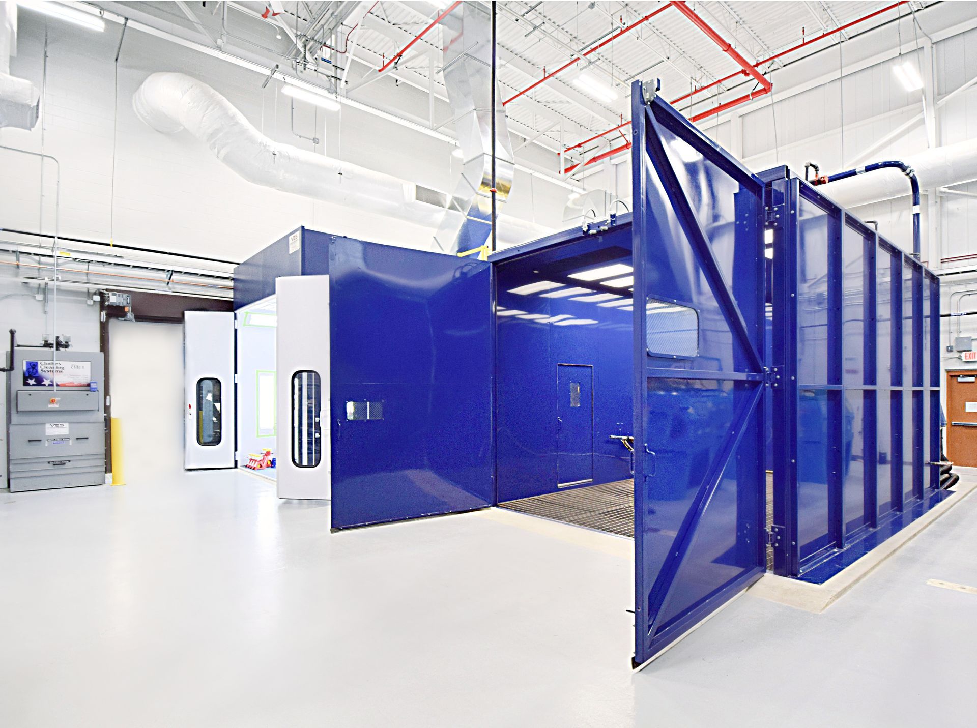 Blue VES blast enclosure and paint booth with open doors inside a facility.