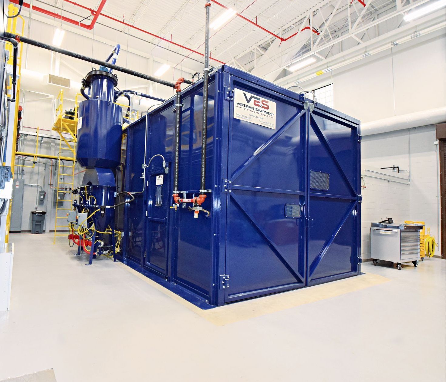 Blue VES blast enclosure and dust collector installed inside a facility.