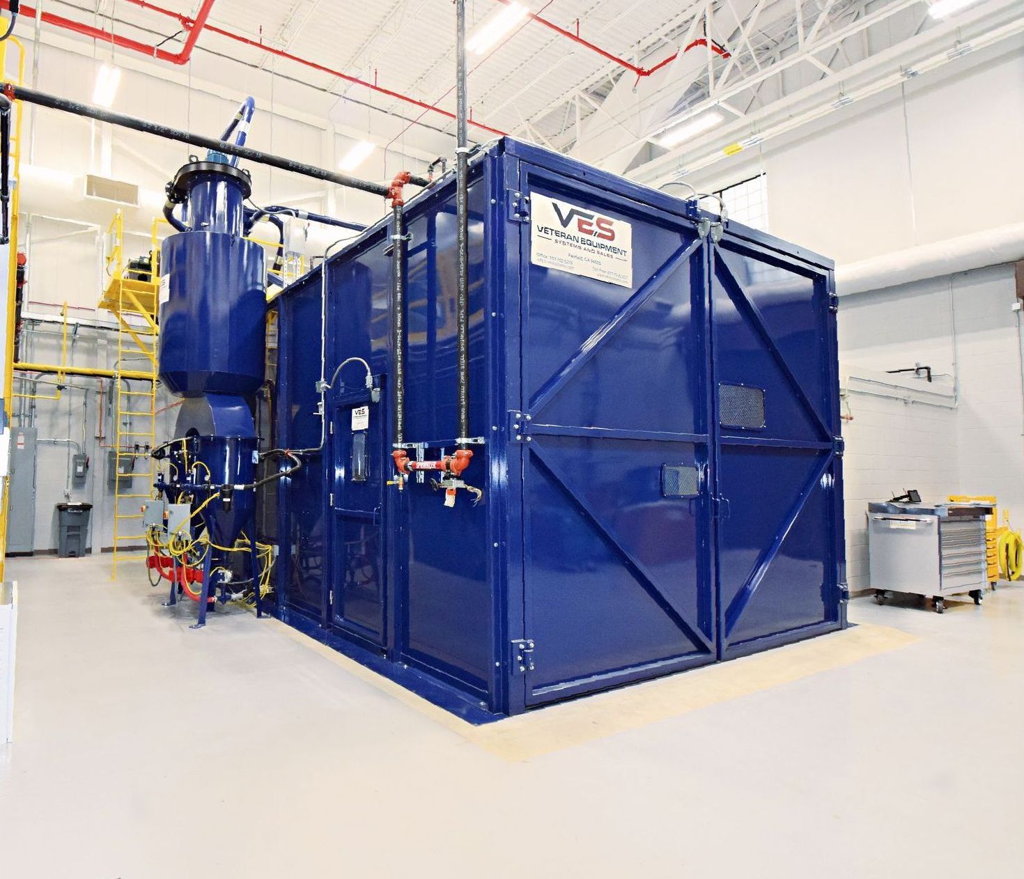 Blue VES blast enclosure with dust collection system installed inside a facility