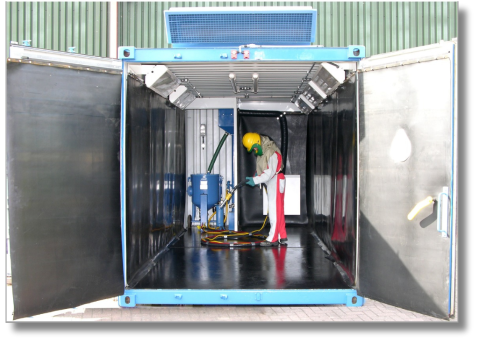 Portable VES containerized blast booth with operator inside wearring PPE and holding a hose.