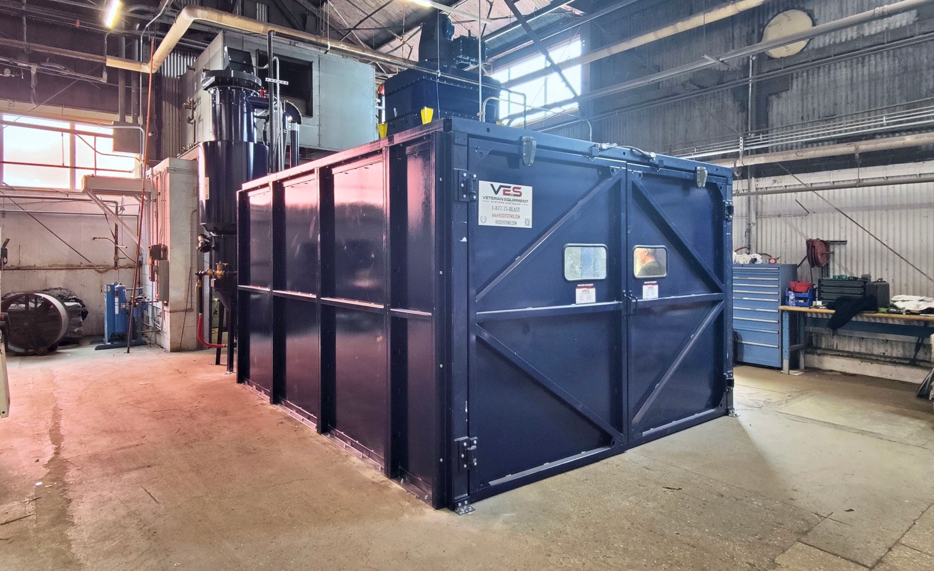 Blue VES blast enclosure and dust collector installed inside a facility.