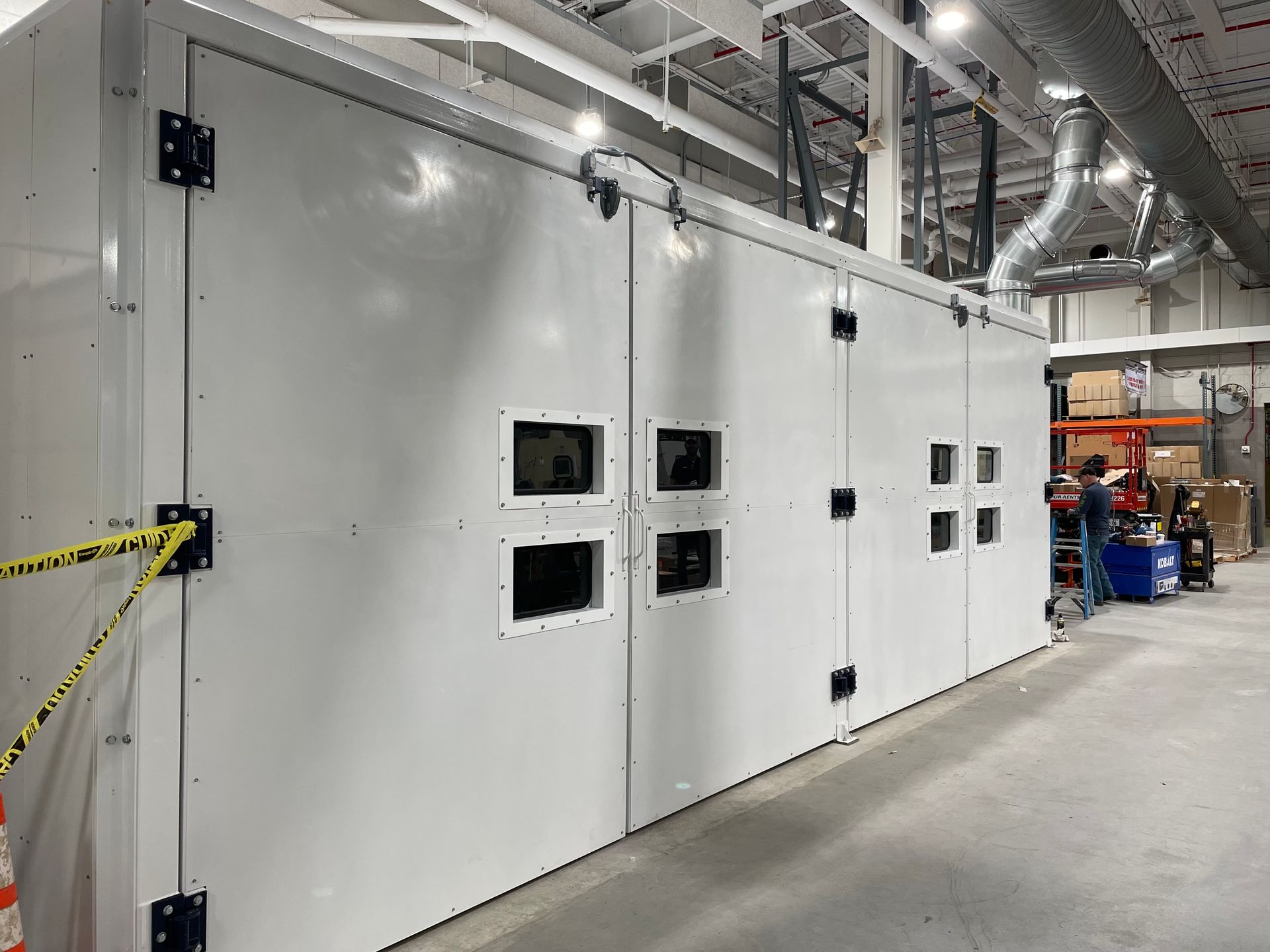 Exterior of large white VES blast enclosure installed inside a facility.