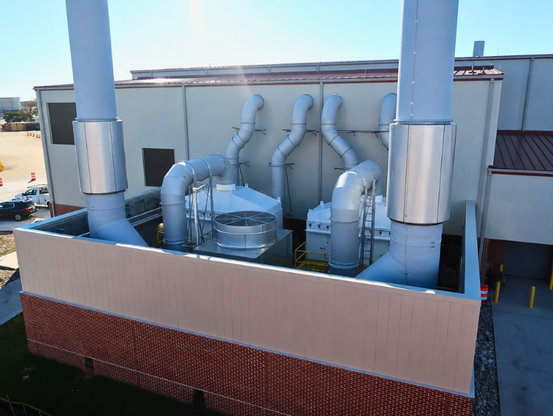 Exterior VES dust collectorsand ventilation ductwork installed along an industrial building.