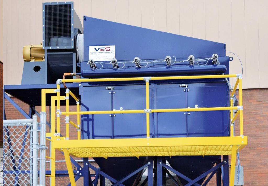 Blue VES dust collector installed outside a building with yellow railing inside open chain link fence