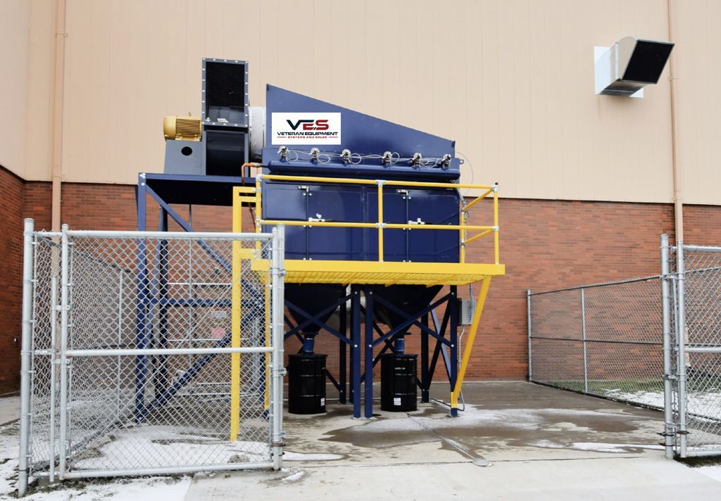 Blue VES dust collector installed outside a building with yellow railing inside open chain link fence