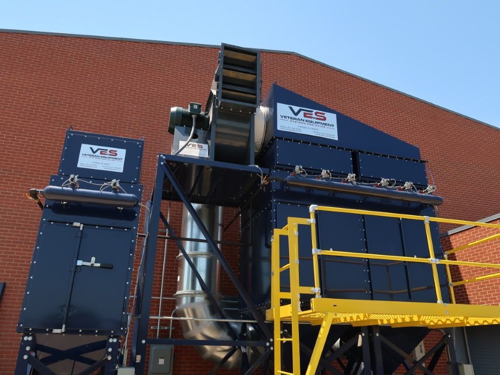 Blue VES dust collector installed outside a building with yellow railing.