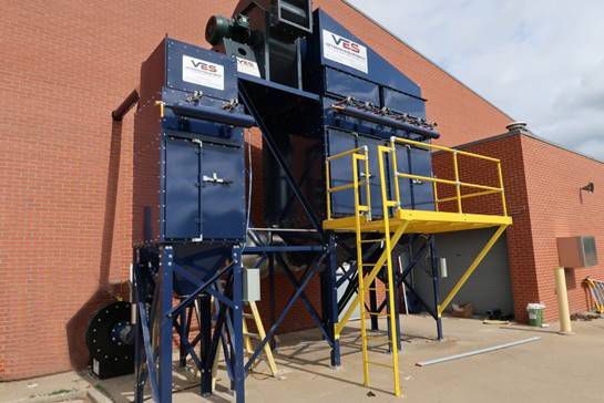 Blue VES dust collector installed outside a building with yellow railing.