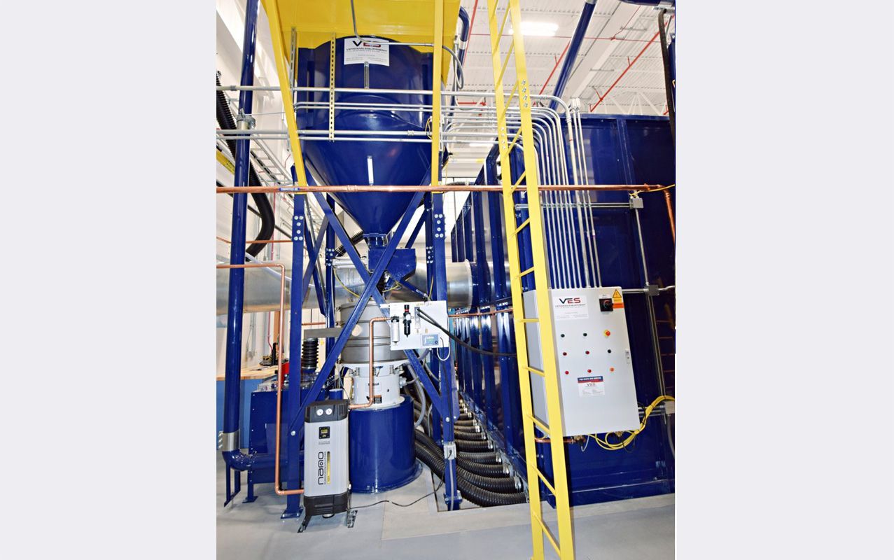Blue VES dense particle separator and pneumatic floor recovery systems next to VES blue blast booth inside a facility