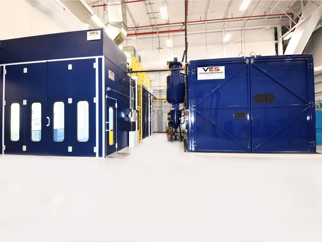 Blue paint booth in a bright industrial setting.