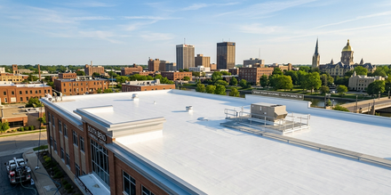City skyline seen from a rooftop with white roof and brick buildings in the foreground