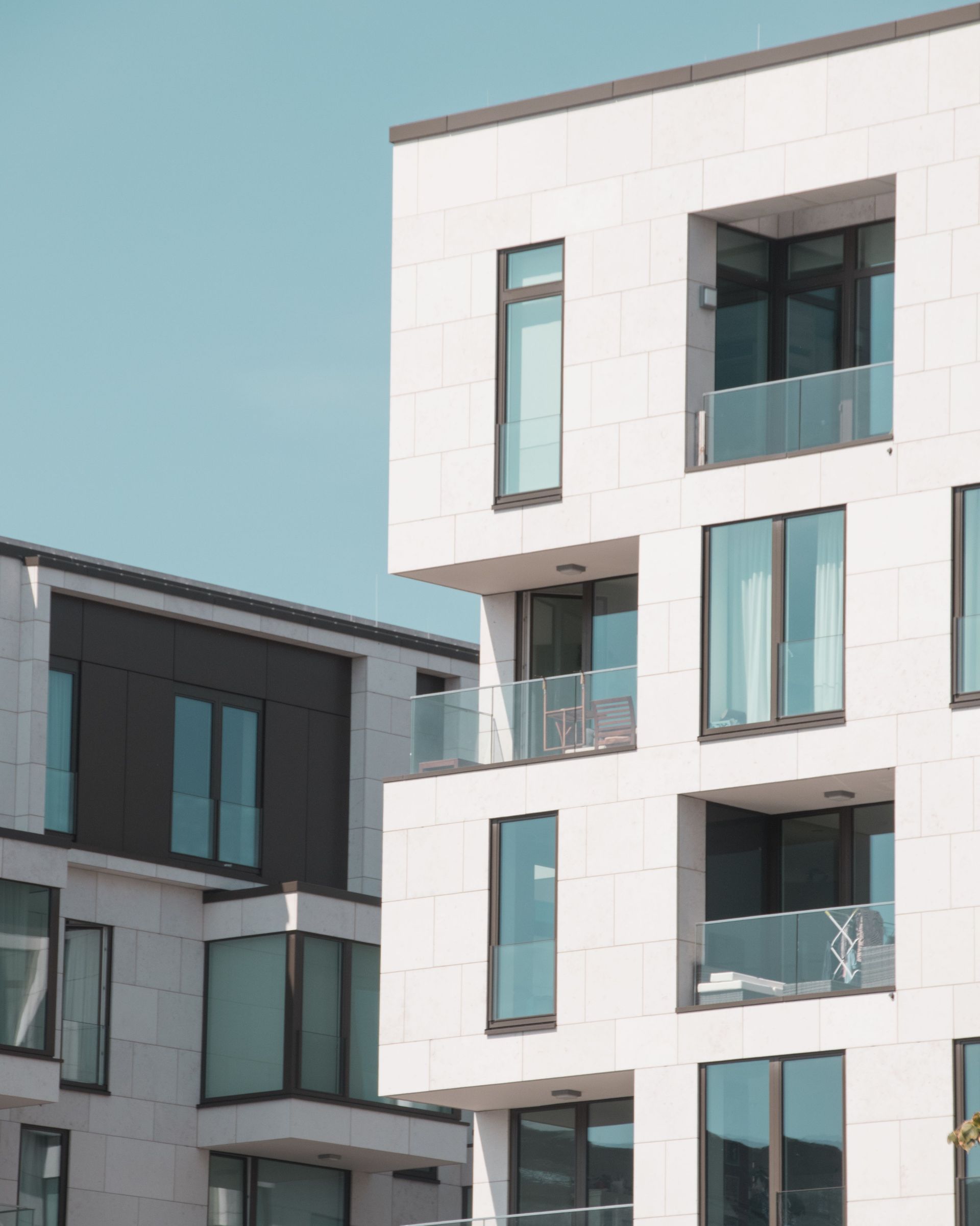Modern apartment buildings with white and gray facades against a clear blue sky