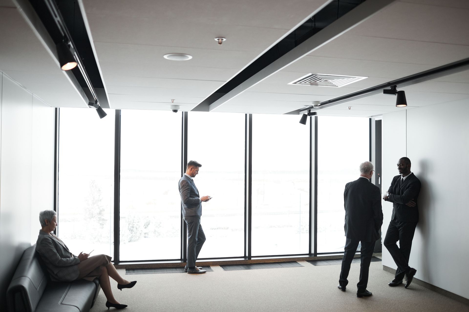 People standing and talking in a bright modern conference room with floor-to-ceiling windows