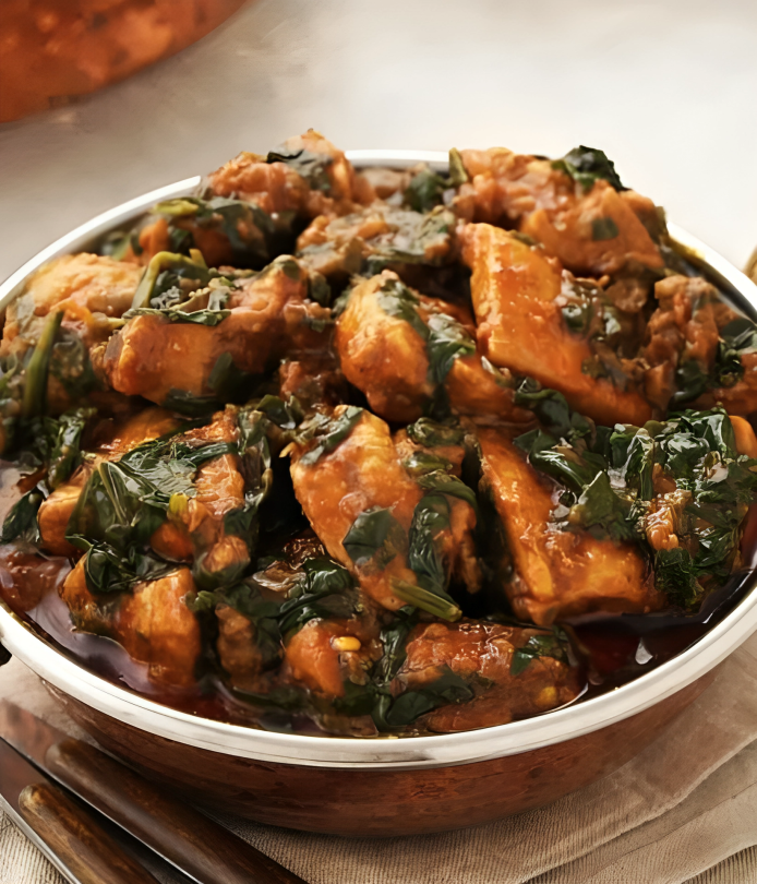 Chicken Saag, a creamy curry with chicken and spinach in a metal bowl.