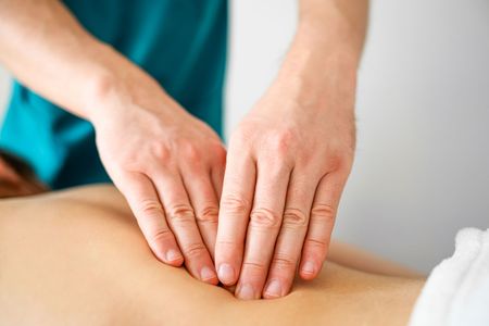 Massage therapist applying focused trigger point pressure to client's upper trapezius muscle during San Diego therapy session