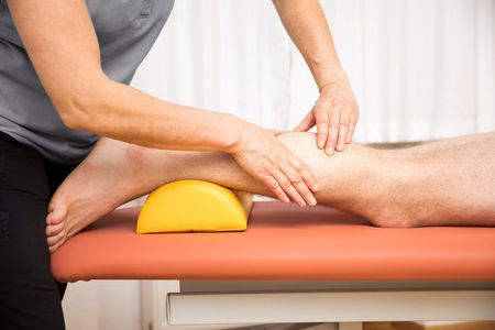 Sports massage therapist working on athletic client's hamstring using deep focused technique in San Diego