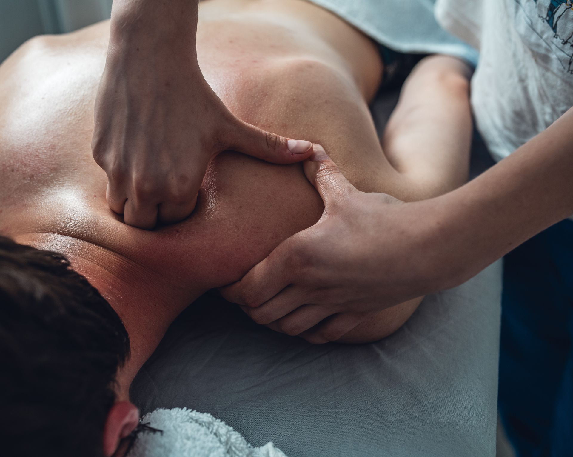 Hands giving a shoulder massage on a person lying face down on a table