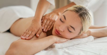 Massage therapist performing long effleurage strokes on a client's back during a Swedish massage in a warm San Diego studio