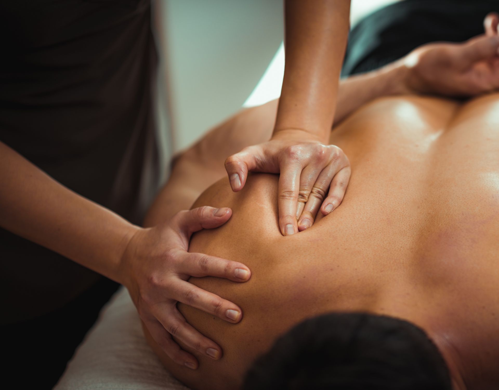 Hands giving a back massage on a person lying face down on a table