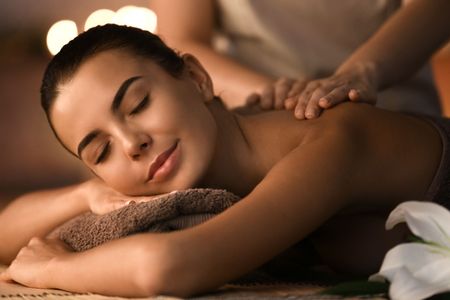 Licensed therapist performing Swedish massage long gliding strokes on client's back in San Diego treatment room
