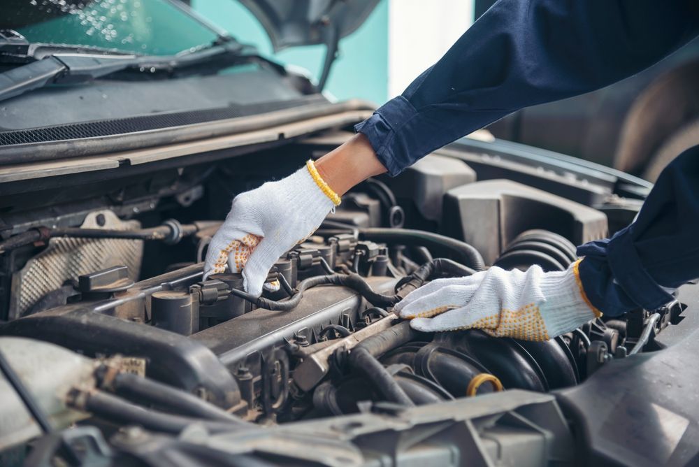 Mechanic's Gloved Hands Working on a Car Engine With the Hood Open — Mareeba Motors In Mareeba, QLD