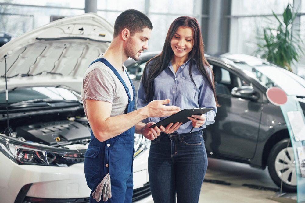 A Mechanic Is Talking To A Woman In A Car Showroom — Mareeba Motors In Mareeba, QLD