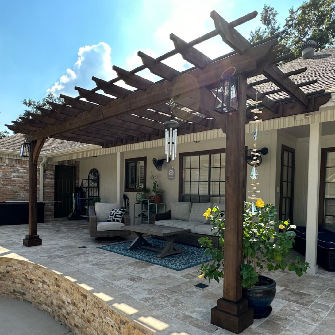 Wooden pergola over a patio with outdoor seating. Wind chimes hang from the structure.