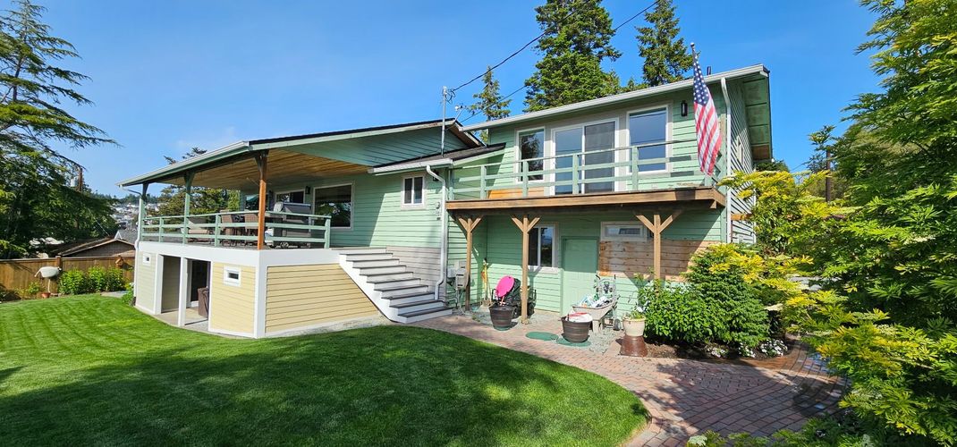 Two-story house with a wraparound porch and landscaped yard on a sunny day