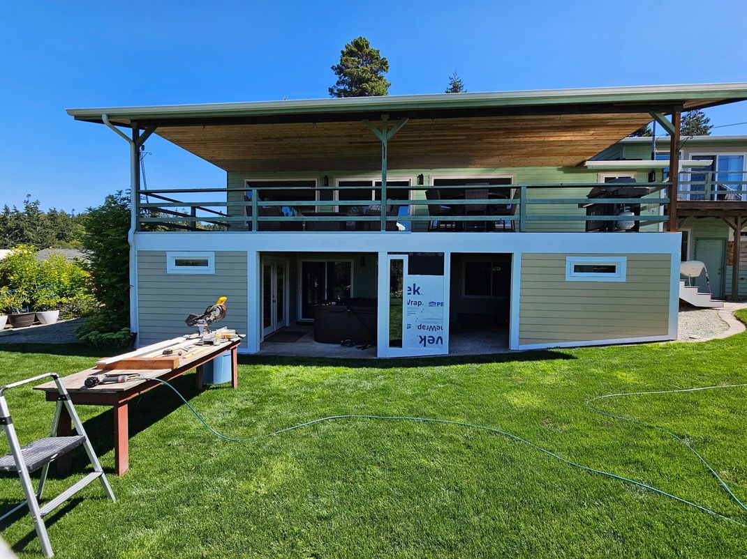 Modern two-story house with a flat roof and green lawn under a clear blue sky