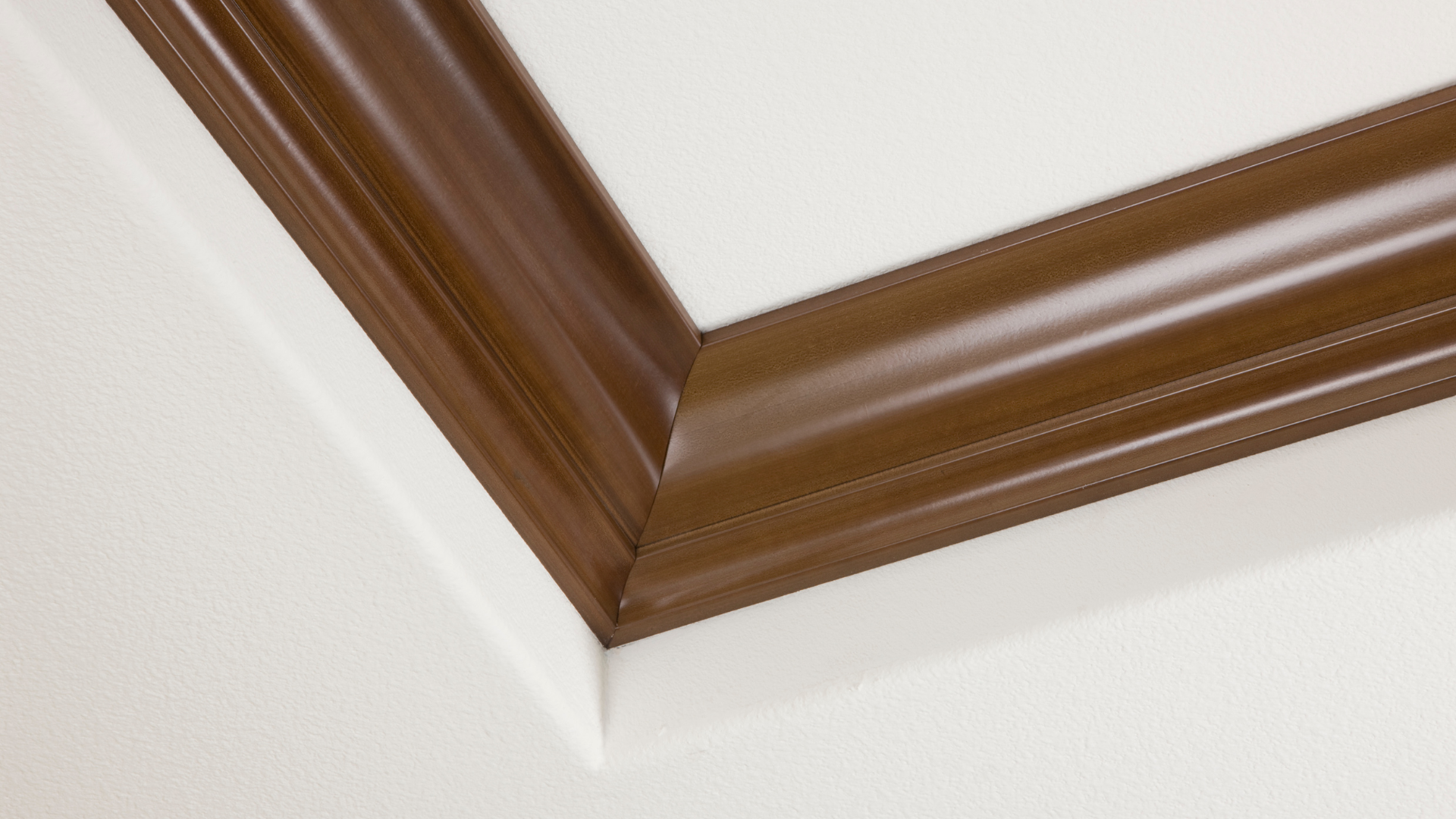 Close-up of brown crown molding on a white ceiling corner