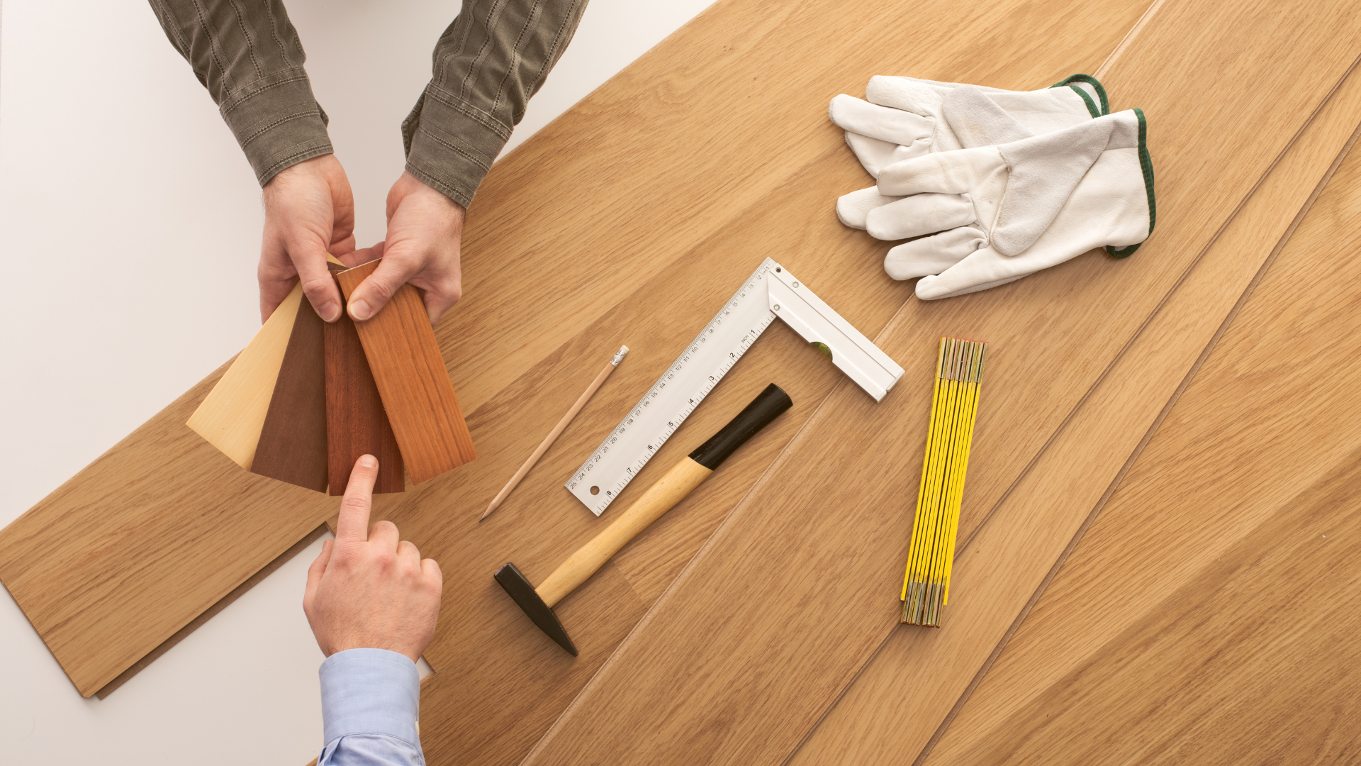 Hands measuring and cutting wood pieces on a worktable with gloves, ruler, and pencil pieces.