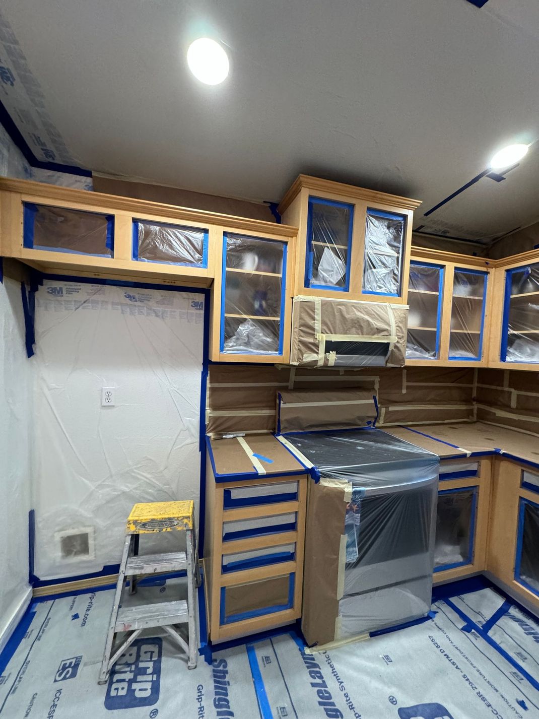 Partially renovated kitchen with wood cabinets, stainless stove, and covered floors and counters