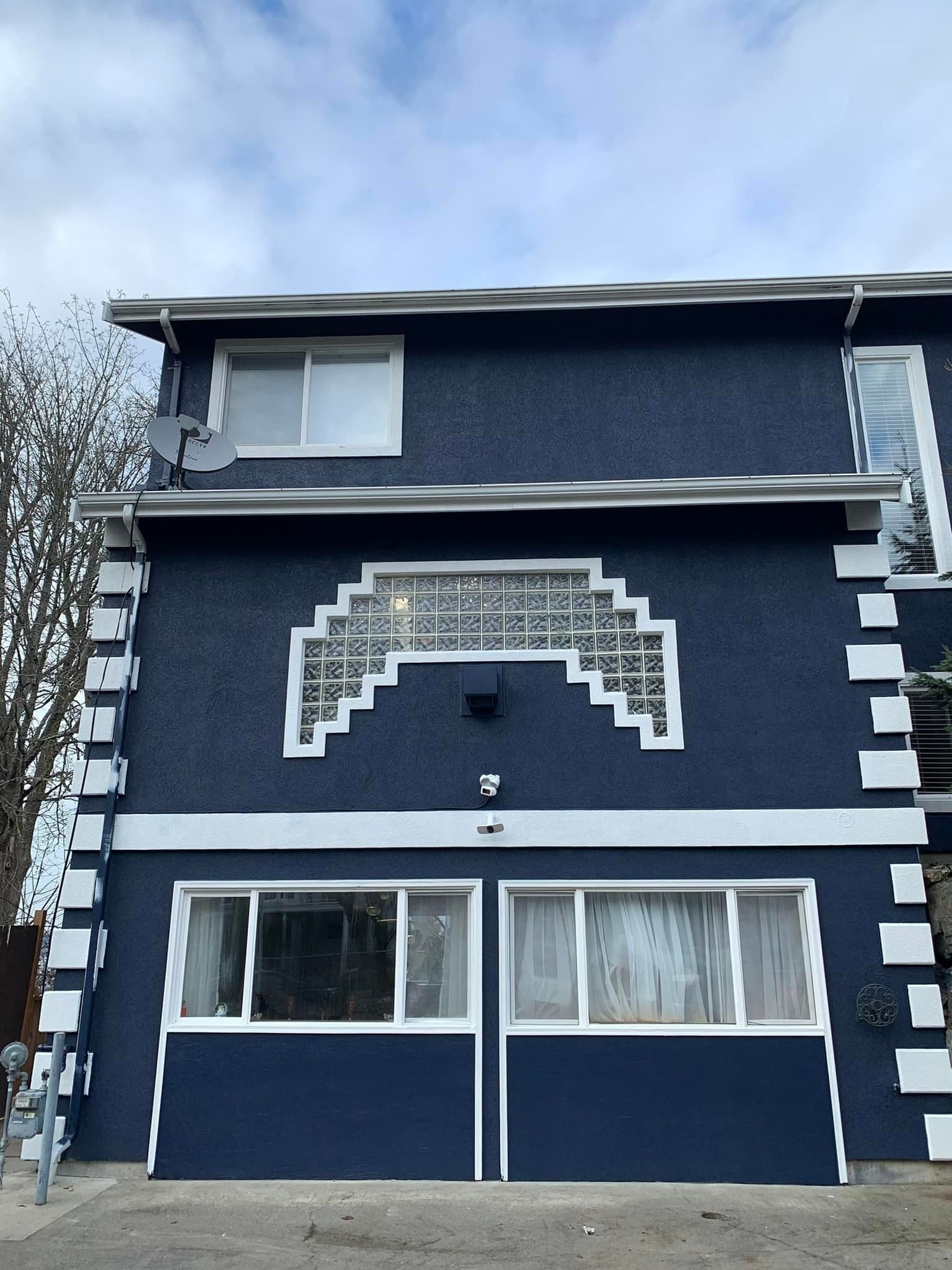 Dark blue two-story house with white trim and an arched decorative facade beneath the roofline.