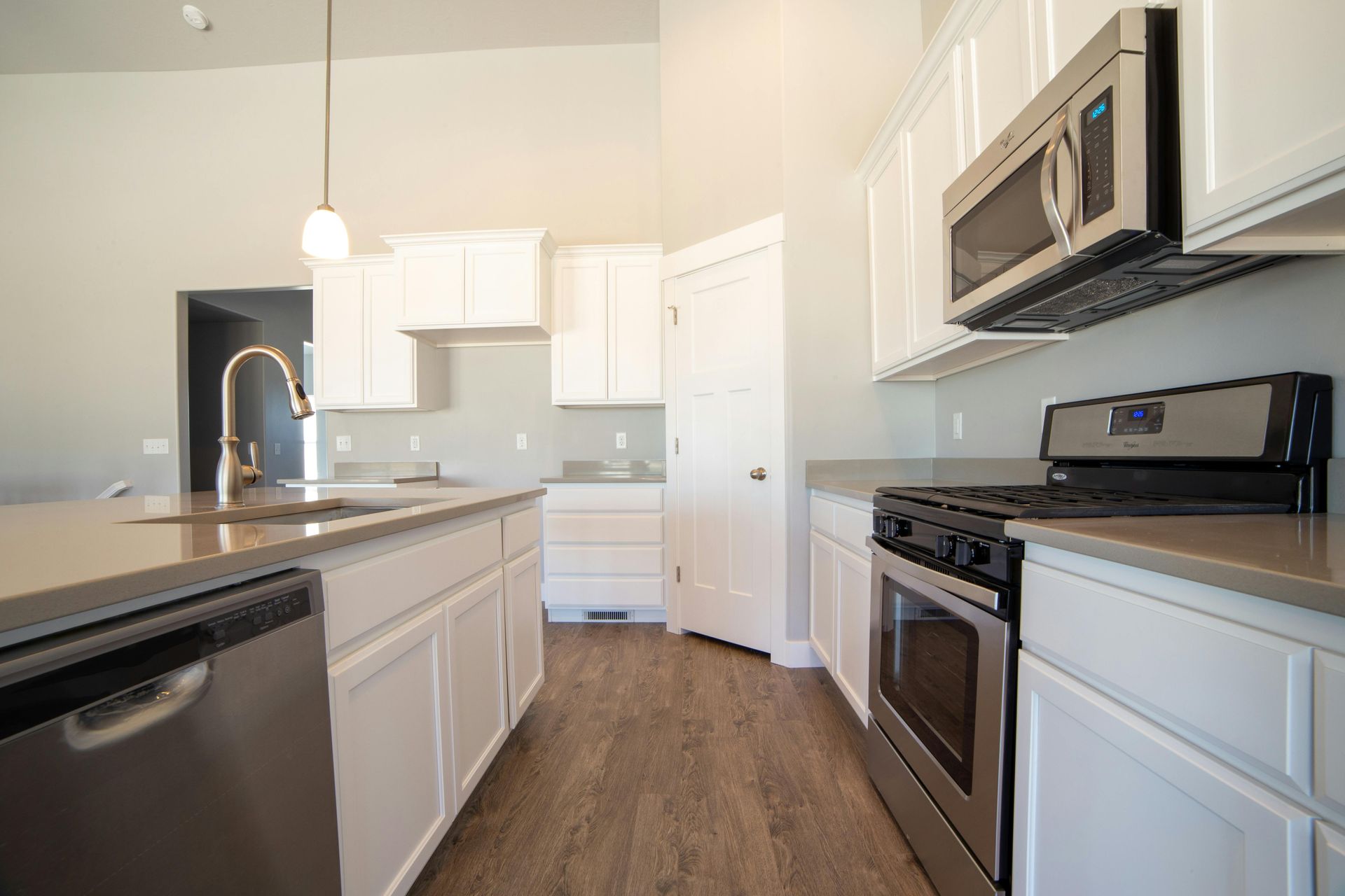 Modern white kitchen with black appliances, wood floors, and a central island